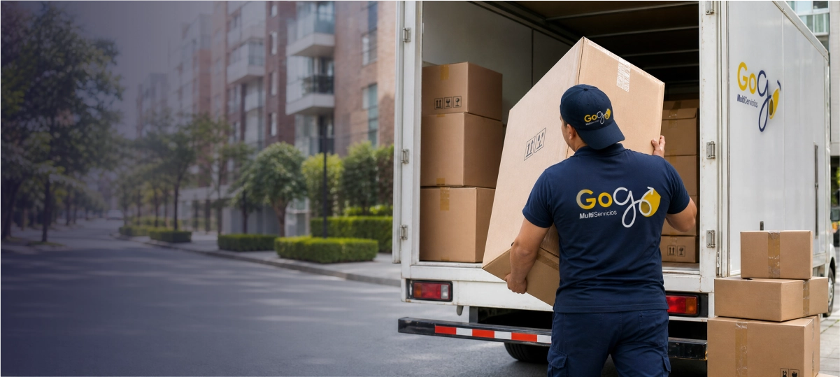 Operario de GoGo Multiservicios cargando una caja en un camión de trasteos junto a otras cajas protegidas